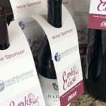 Bottles of wine with a sleeve over the top of the bottle displaying the Corks for a Cause and NMS logos.